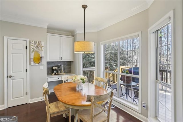 dining area with dark wood-type flooring, baseboards, and ornamental molding