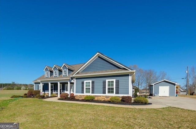 view of front of property with a front yard, covered porch, an outdoor structure, stone siding, and a detached garage