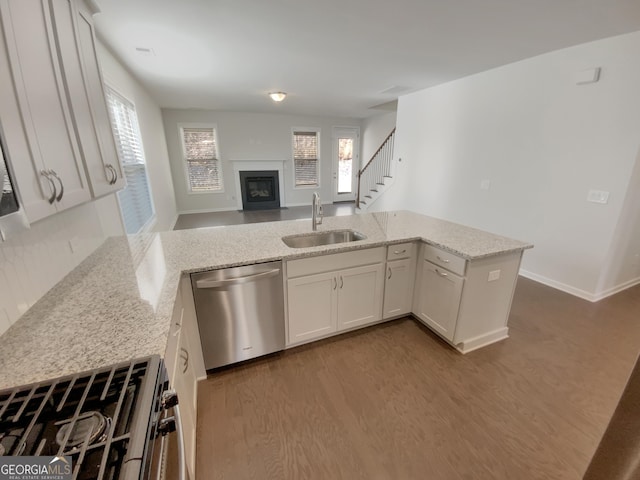 kitchen with range with gas stovetop, light stone counters, dark wood-style flooring, a sink, and stainless steel dishwasher