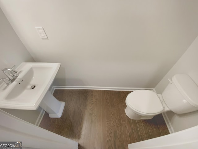 bathroom featuring a sink, toilet, baseboards, and wood finished floors