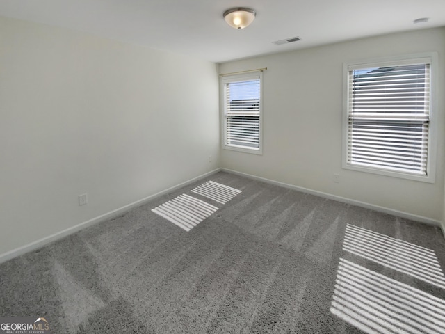 unfurnished room featuring visible vents, baseboards, and carpet