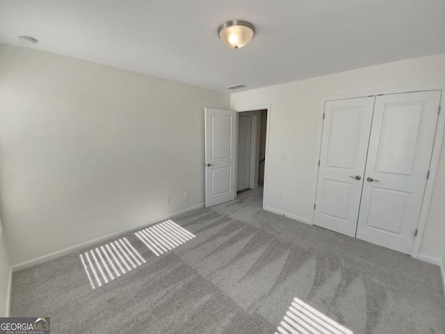 unfurnished bedroom featuring visible vents, carpet floors, baseboards, and a closet