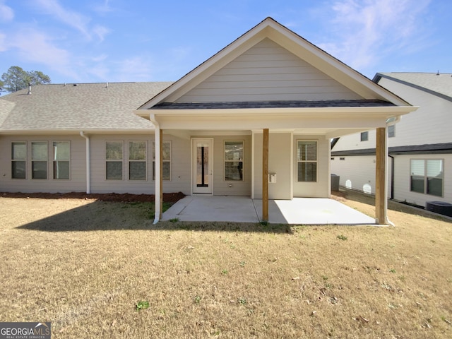 rear view of house with a lawn, a shingled roof, and a patio