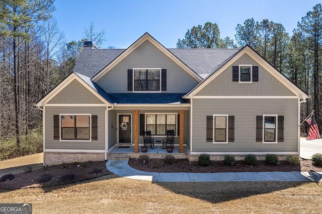 craftsman house featuring a porch, a chimney, and a shingled roof