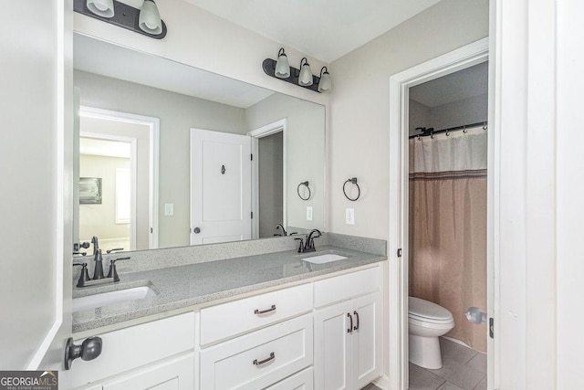 bathroom with a sink, toilet, double vanity, and tile patterned floors