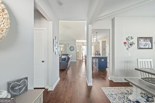 hallway featuring dark wood-style floors, baseboards, and a sink