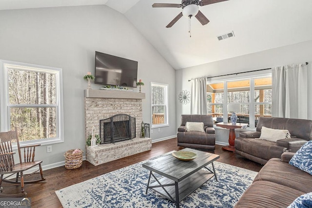 living area featuring visible vents, a fireplace with raised hearth, baseboards, wood finished floors, and high vaulted ceiling