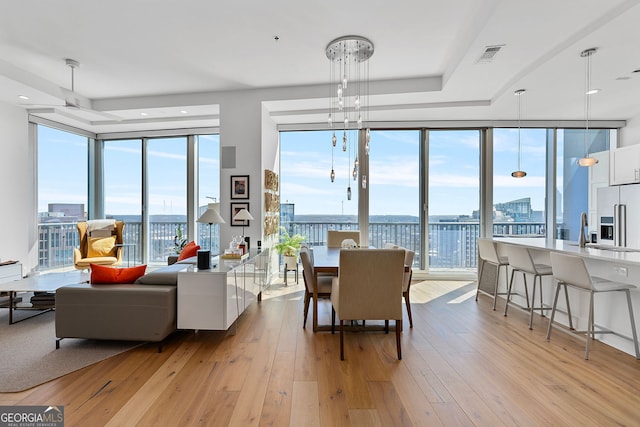 dining area featuring a view of city, visible vents, light wood-type flooring, and expansive windows