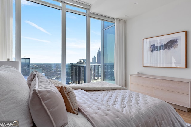 bedroom featuring a city view, a wall of windows, and light wood finished floors