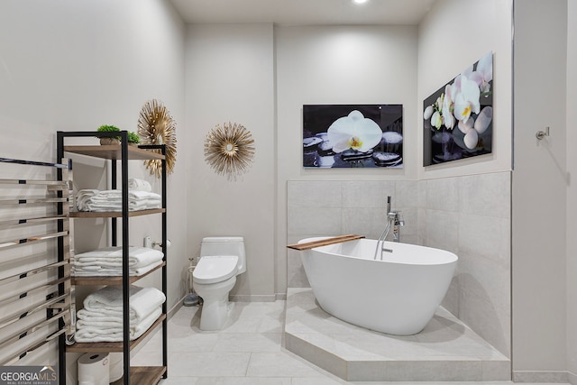 full bath featuring tile patterned flooring, toilet, tile walls, and a freestanding tub