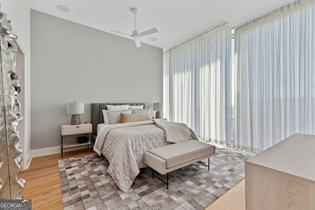 bedroom with baseboards, light wood-style flooring, a ceiling fan, and lofted ceiling