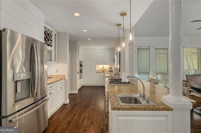 kitchen with dark wood-type flooring, decorative light fixtures, white cabinets, stainless steel appliances, and a sink