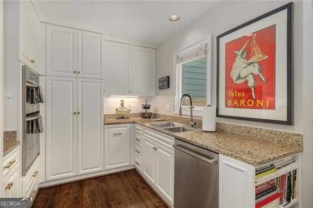 kitchen featuring a sink, stainless steel dishwasher, dark wood finished floors, and white cabinetry