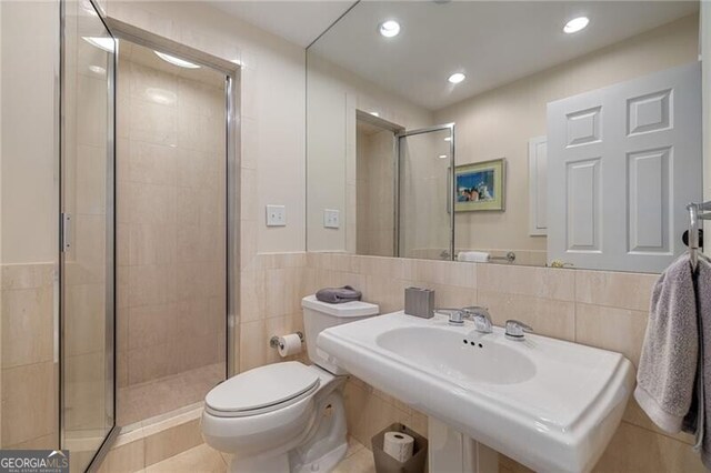 bathroom featuring toilet, recessed lighting, a stall shower, tile walls, and a sink