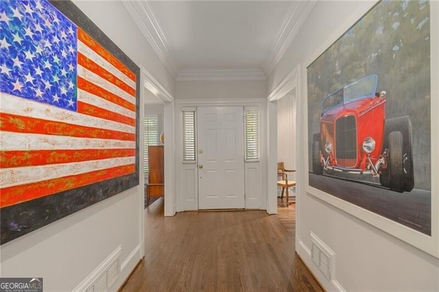 hall featuring visible vents, wood finished floors, and ornamental molding
