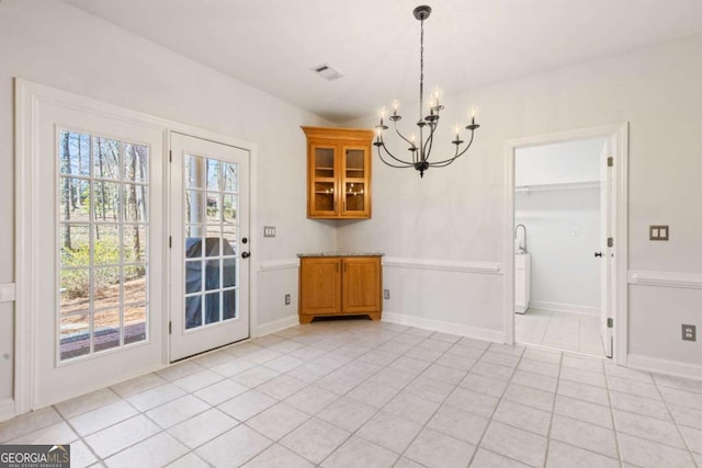 unfurnished dining area with light tile patterned floors, visible vents, baseboards, and an inviting chandelier