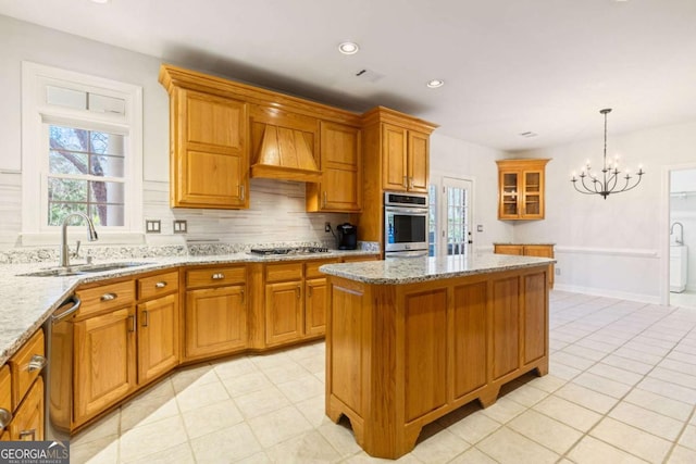 kitchen with a sink, appliances with stainless steel finishes, custom range hood, a chandelier, and a kitchen island