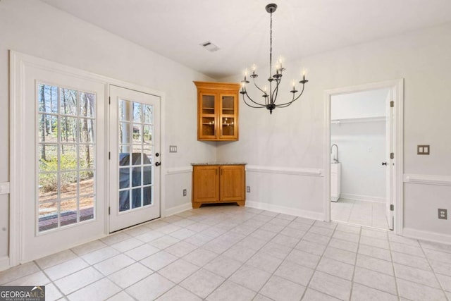 unfurnished dining area with a chandelier and light tile patterned flooring