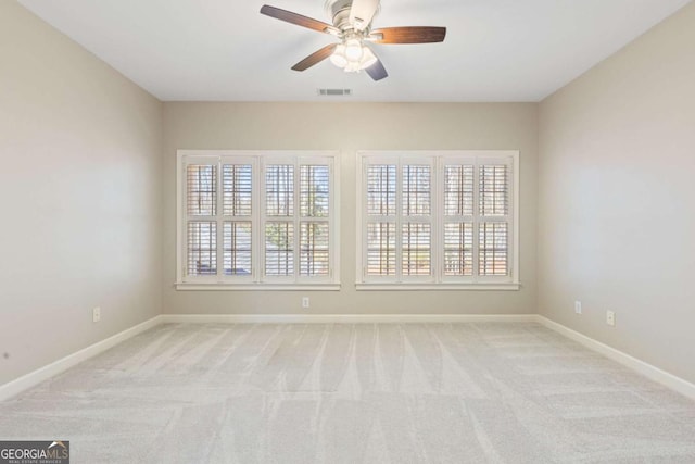 unfurnished room with visible vents, baseboards, light colored carpet, and ceiling fan