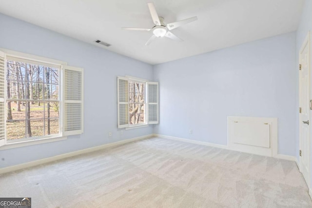 carpeted spare room featuring visible vents, ceiling fan, and baseboards