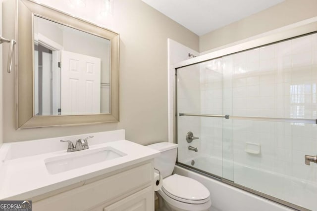 bathroom with vanity, toilet, and bath / shower combo with glass door