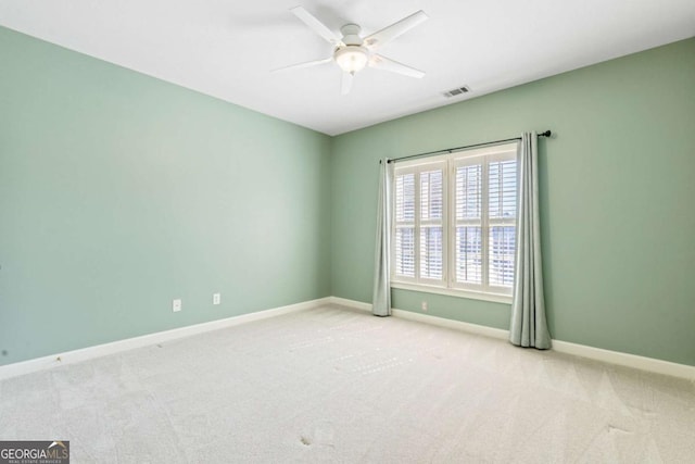 spare room featuring carpet flooring, visible vents, baseboards, and ceiling fan