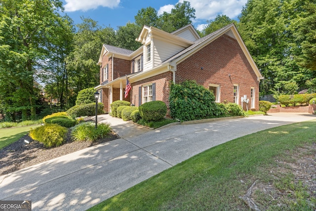 view of property exterior with brick siding and a lawn