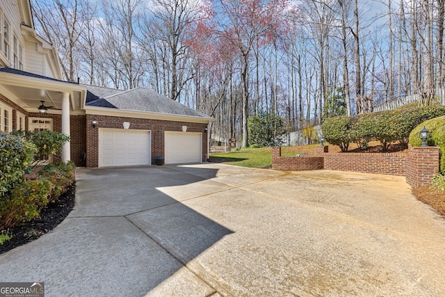 view of home's exterior featuring brick siding, concrete driveway, a garage, and roof with shingles
