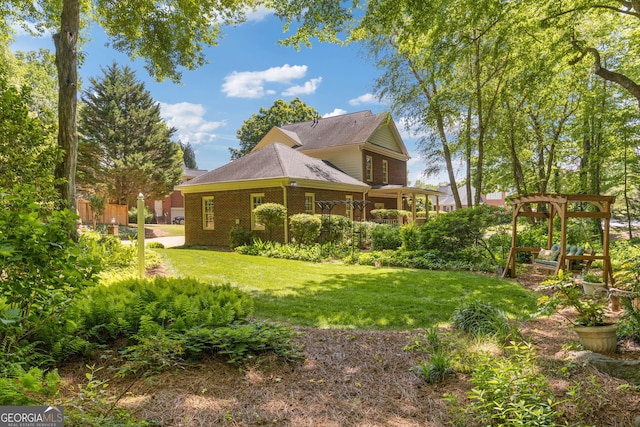 back of house with a lawn, brick siding, and a gazebo