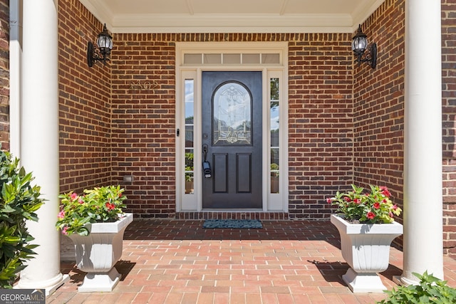 entrance to property with a porch and brick siding