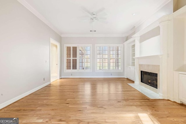 unfurnished living room with a premium fireplace, built in shelves, light wood-type flooring, and ornamental molding