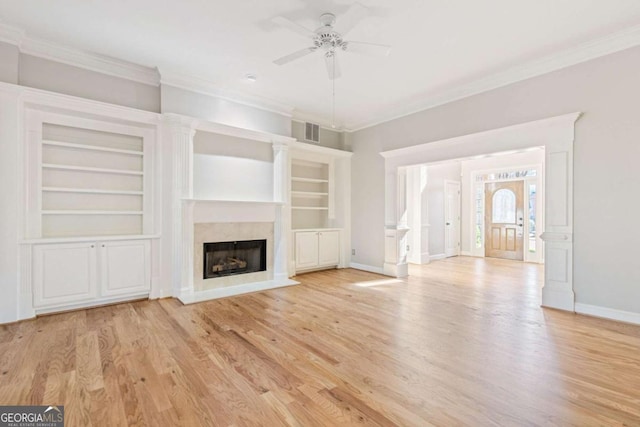 unfurnished living room featuring visible vents, built in shelves, ornamental molding, a fireplace, and light wood-style floors