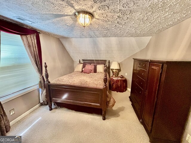bedroom with vaulted ceiling, light carpet, and a textured ceiling