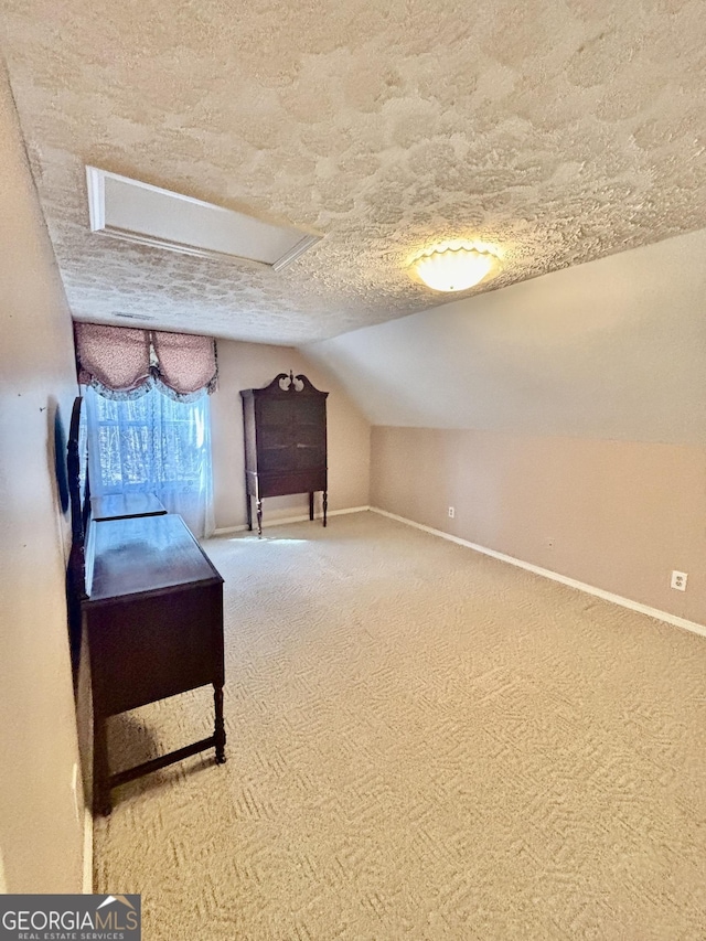 unfurnished bedroom featuring vaulted ceiling, carpet, baseboards, and a textured ceiling