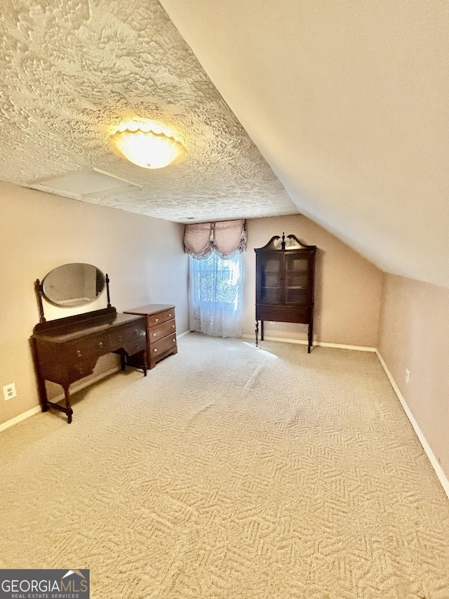 carpeted bedroom with vaulted ceiling, baseboards, and a textured ceiling