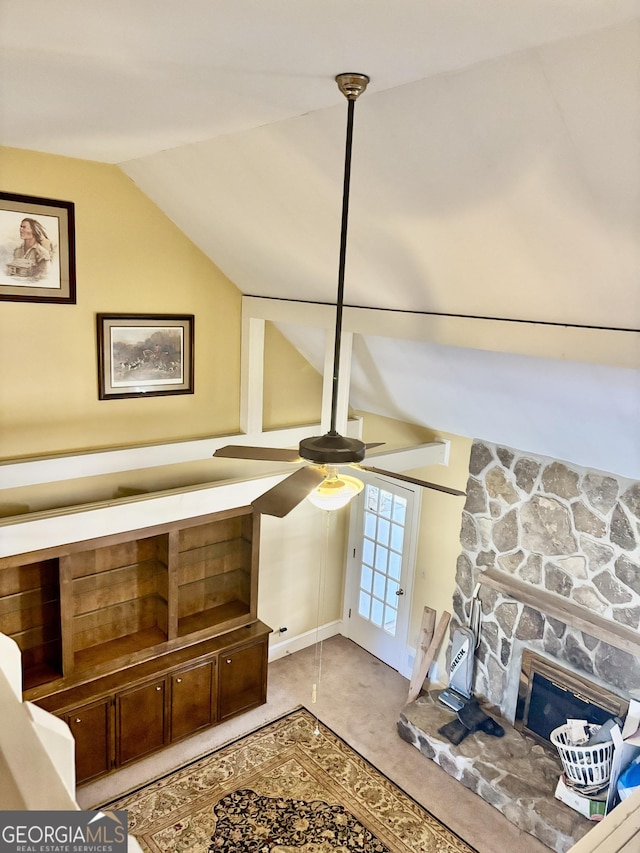 details featuring a stone fireplace, a ceiling fan, and carpet floors