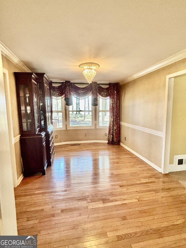 interior space with light wood-type flooring, visible vents, and ornamental molding