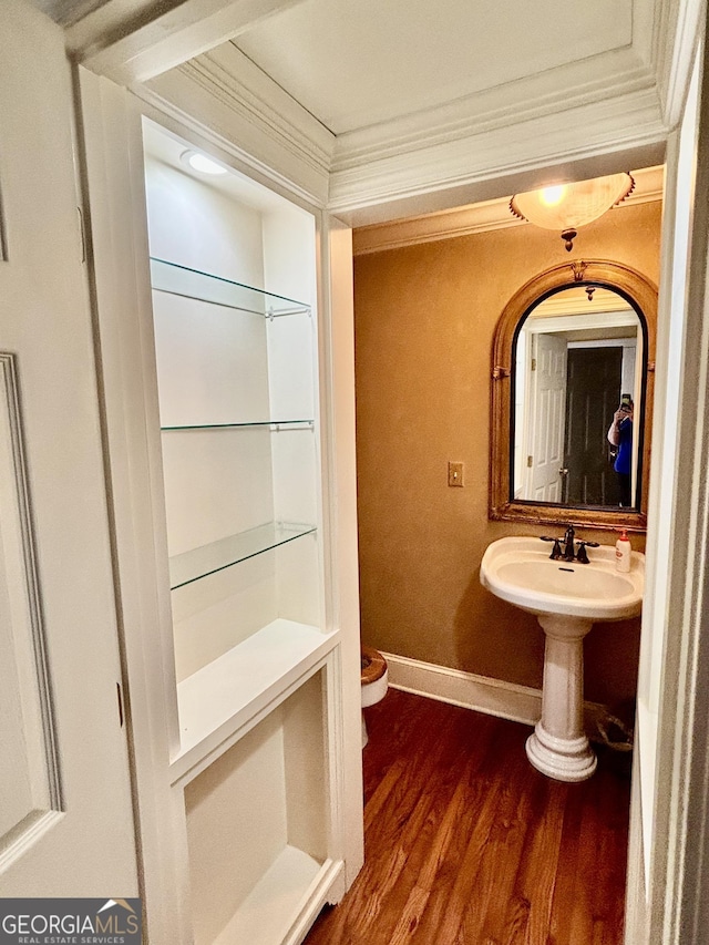 bathroom with toilet, wood finished floors, baseboards, and ornamental molding