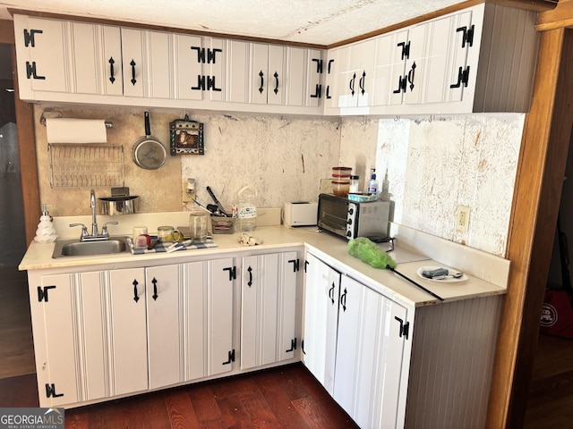 kitchen with dark wood-type flooring, a sink, white cabinets, a toaster, and light countertops