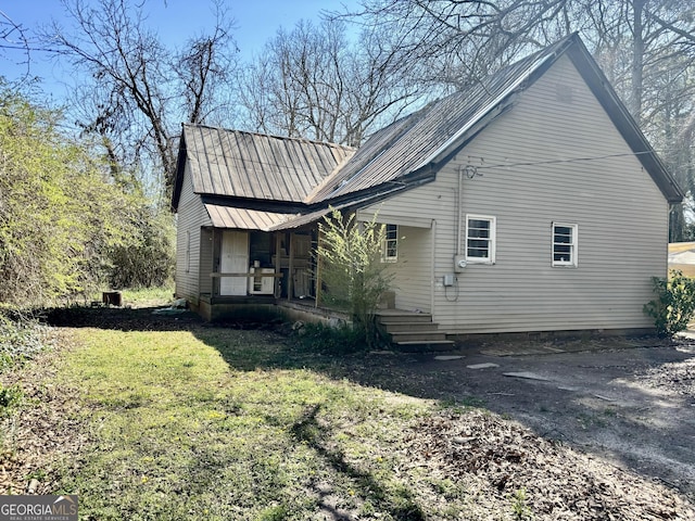 view of side of property with a porch, metal roof, a yard, a carport, and driveway