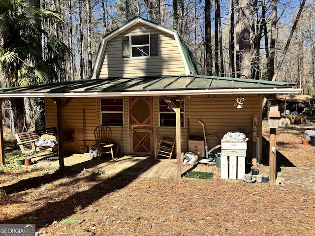 rear view of property featuring metal roof, a gambrel roof, and a standing seam roof