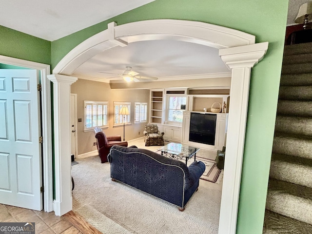 living room featuring crown molding, ceiling fan, stairs, carpet floors, and decorative columns