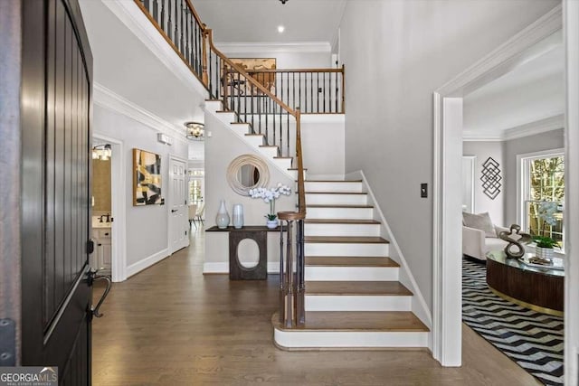 foyer entrance with dark wood finished floors, stairway, crown molding, and a towering ceiling