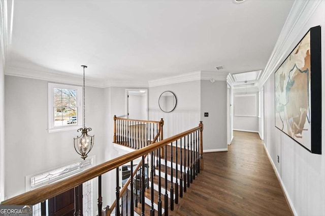 corridor with crown molding, attic access, an upstairs landing, an inviting chandelier, and wood finished floors