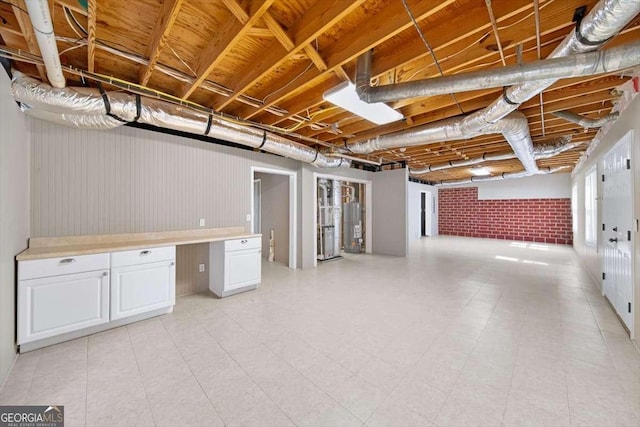 below grade area with gas water heater, built in desk, and brick wall