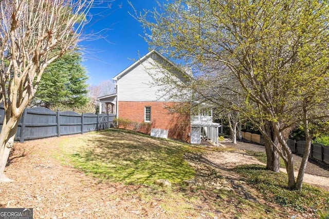 exterior space featuring brick siding, a yard, and fence