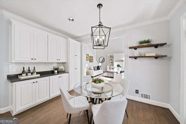 dining room with visible vents, ornamental molding, baseboards, and dark wood-style flooring