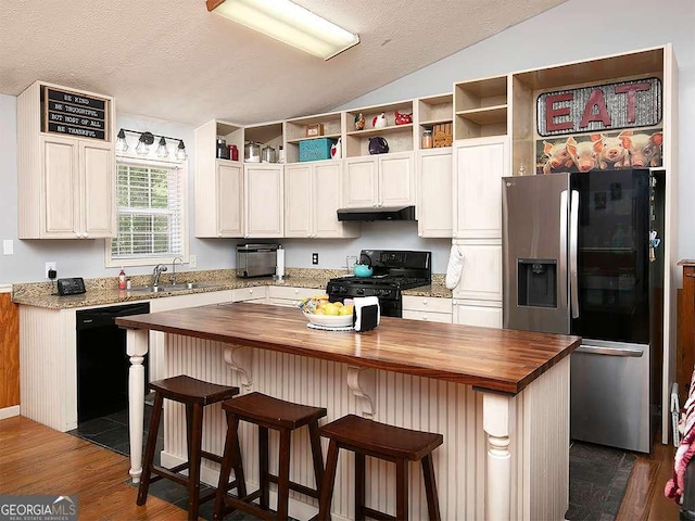 kitchen featuring under cabinet range hood, wooden counters, black appliances, and vaulted ceiling