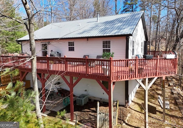 back of house with a wooden deck, central AC unit, and metal roof