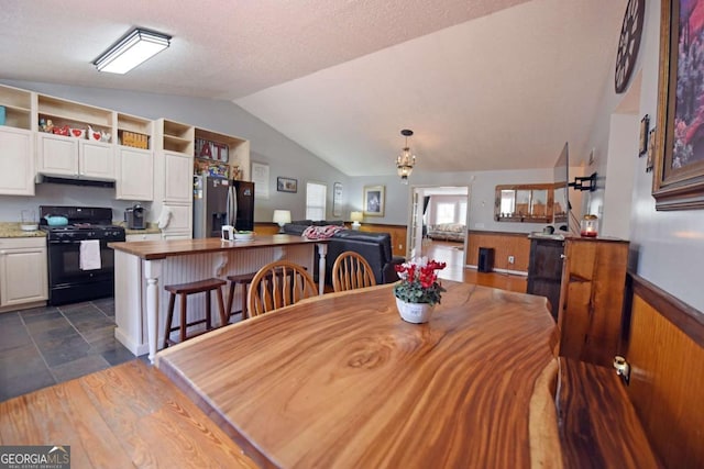 dining space with lofted ceiling and a wainscoted wall